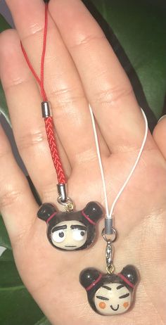 someone is holding two charms in their hand, one with a monkey head on it