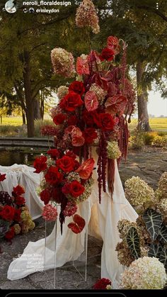 a bunch of flowers that are on some kind of stand in front of a tree