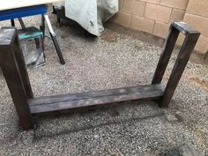 a wooden bench sitting on top of a gravel covered ground next to a wall and table