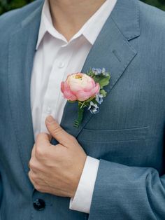 a man wearing a blue suit and pink flower boutonniere on his lapel