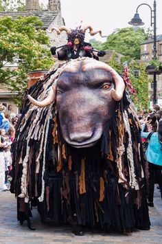 an animal with horns and feathers on it's head is walking down the street