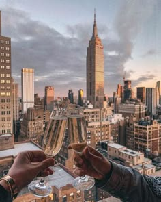 two people toasting with wine glasses in front of a cityscape