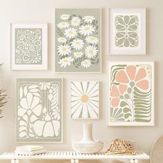 a white table topped with lots of pictures and vase filled with flowers next to a wall