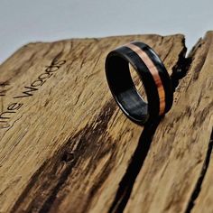 a black ring with an orange stripe is sitting on top of a piece of wood