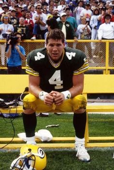 a football player sitting on the sidelines in front of a stadium full of people