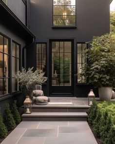 a black house with steps leading up to the front door and plants on either side