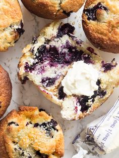 blueberry muffins with butter and icing sitting on a marble counter top