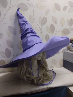 a wig with a purple hat on top of it next to a wallpapered background