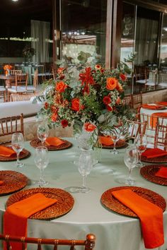 the table is set with orange napkins and place settings