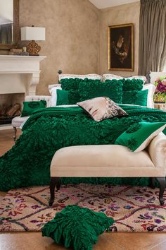 a bed with green comforter and pillows in a room next to a fireplace area