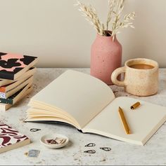 an open book sitting on top of a table next to a cup of coffee and other items