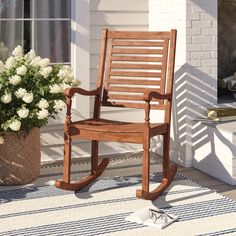 a wooden rocking chair sitting on top of a rug next to a potted plant