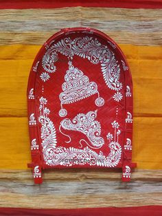 a red and white tray with an ornate design on the front, sitting on a wooden surface