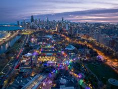 an aerial view of a city at night with lights on and carnival rides in the foreground