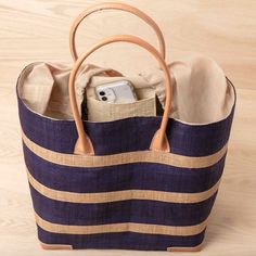 Looking for a unique and gorgeous beach tote? This raffia bag is made from high-quality raffia palm with a natural and navy blue alternating stripe. These bags have a useful cotton pull closure, inside pocket, and beautiful zebu leather handles, and are big enough to handle even the longest beach days! All our raffia totes are made by a fair-trade woman-owned company in Madagascar. 100% raffia eco-friendly dyes zebu leather handle inside pocket cotton pull closure 17.5" x 13.5" x 8" 7" handle dr Striped Rectangular Straw Bag For Daily Use, Striped Rectangular Straw Bag With Braided Handles, Striped Woven Straw Bag For Everyday Use, Summer Vacation Beach Bag With Striped Lining, Striped Straw Tote Bag For Everyday Use, Travel Striped Straw Bag With Braided Handles, Striped Straw Bag With Braided Handles For Everyday Use, Everyday Striped Straw Bag With Braided Handles, Rectangular Vacation Bags With Striped Lining