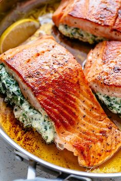 two salmons with spinach and cheese in a pan