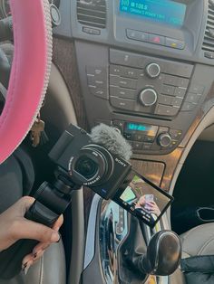 a person holding a camera in their hand and recording something on the car dash board