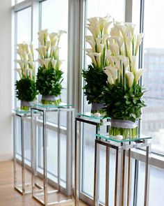 three glass vases with flowers in them sitting on a window sill next to each other