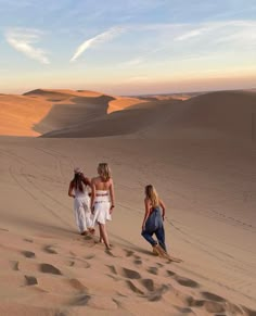 three girls are walking in the sand dunes