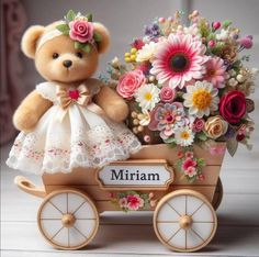 a teddy bear sitting on top of a wooden carriage filled with flowers