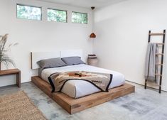 a bedroom with a large bed and two windows on the wall above it, along with a rug