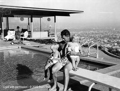 a woman and child sitting on the edge of a swimming pool