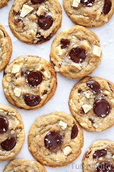 chocolate chip cookies on a baking sheet with white and brown icing in the middle