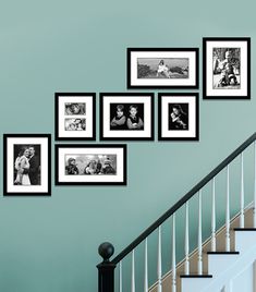 black and white photos hanging on the wall next to a banister with stairs leading up