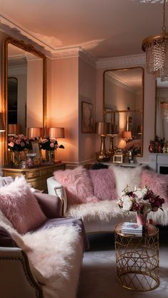 a living room filled with lots of furniture and pink pillows on top of it's couches