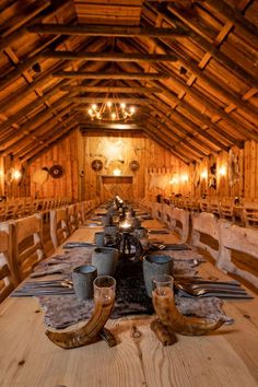 a long table is set up in the middle of a room with wooden walls and beams