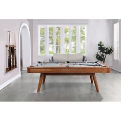 a pool table in the middle of a room with a couch and potted plant