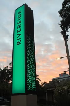 a large sign is lit up in front of a building at sunset with the words riverside on it