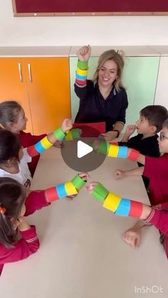 a woman standing in front of a group of children holding up colorful sticks with their hands