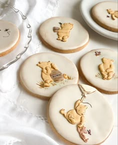 cookies decorated to look like winnie the pooh are on a table with white linens