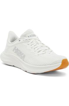 a women's white athletic shoe with an orange heel and laces on the side