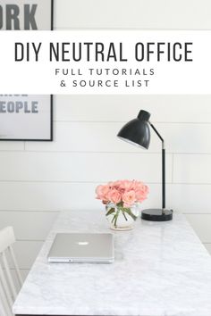 a white desk with flowers and a laptop on it in front of a black lamp that reads diy neutral office