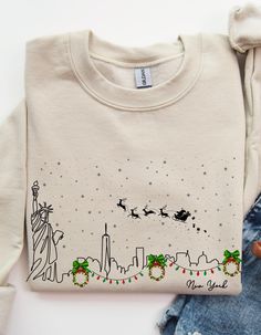 a sweater with the statue of liberty on it next to ripped jeans and a teddy bear