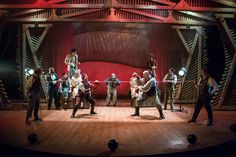 a group of people standing on top of a wooden floor in front of a stage