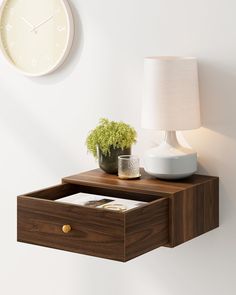 a wall mounted shelf with a plant and a lamp on it next to a clock