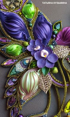 an elaborately designed piece of art with purple flowers and green leaves