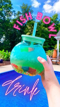 a hand holding a drink in front of a pool with the words fish bowl on it