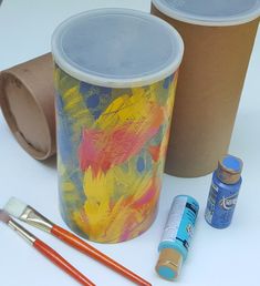 some craft supplies are laying out on a white table with cups and paintbrushes