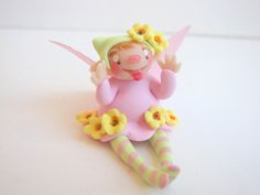 a toy doll sitting on top of a white table next to yellow and pink flowers