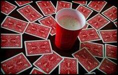 a red cup sitting on top of a table covered in playing cards