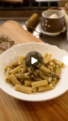 a white bowl filled with pasta on top of a wooden table