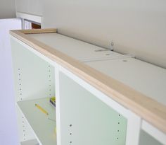 an empty room with white shelves and wooden counter tops, in the process of being built