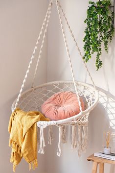 a hammock hanging from the wall with a pillow and throw pillows on it