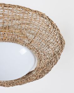 a wicker basket hanging from the ceiling with a white light fixture in front of it