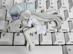 a white doll laying on top of a computer keyboard