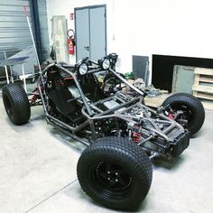 a car is parked in a garage with large tires on the front and rear wheels